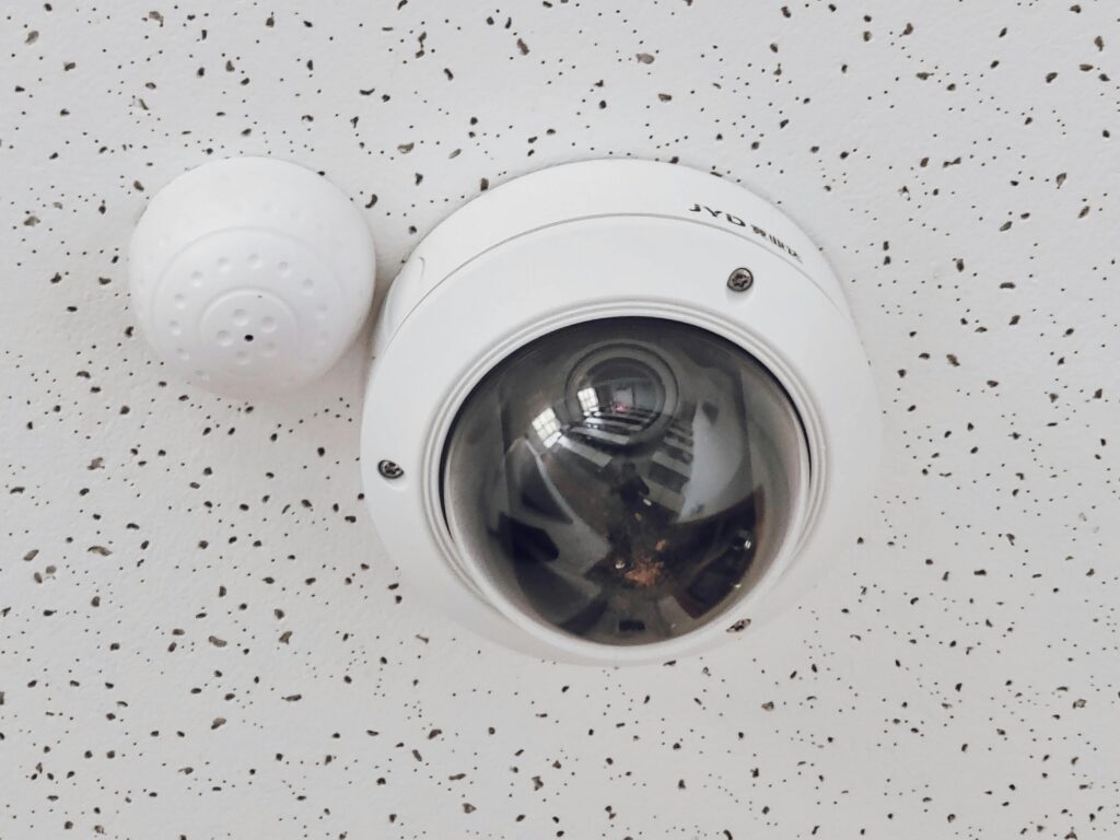 pexels-photo-7508684-7508684 Close-up of a round dome surveillance camera installed on a speckled ceiling for security monitoring.